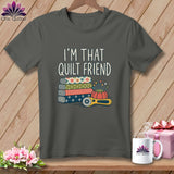 A dark gray t-shirt with the text I'M THAT QUILT FRIEND above stacked fabric, pins, and a rotary cutter.