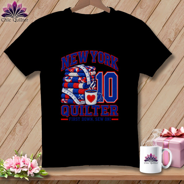 Black t-shirt featuring a New York Quilter graphic with a folded quilt, measuring tape, and mug.
