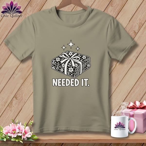 T-shirt with a graphic of folded fabric bundles with a bow and the text "NEEDED IT."