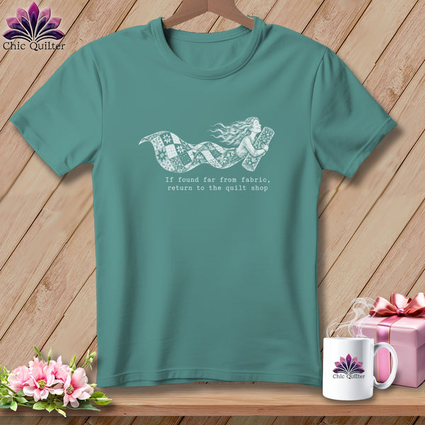 Teal t-shirt with a girl flying on a quilt trail, text reads "return to the quilt shop".
